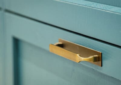 Closeup of a modern kitchen cabinet handle on our teal kitchen Mangan Woodcraft
